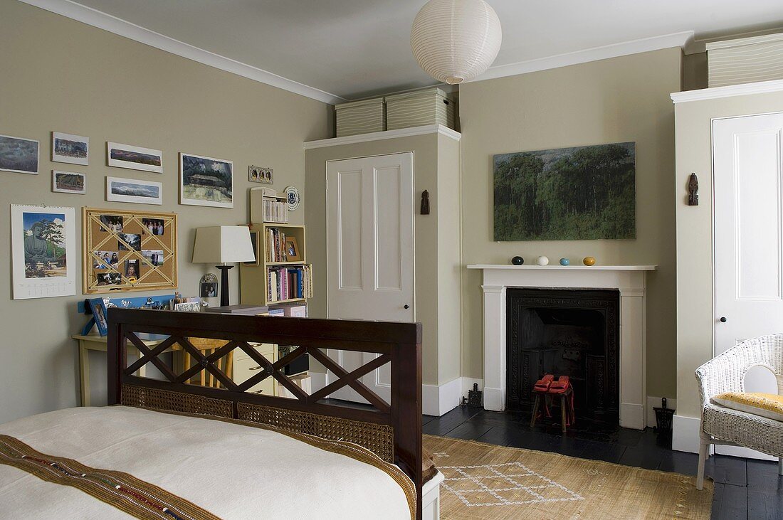 A bedroom with a fireplace between two built-in wardrobes against a grey wall