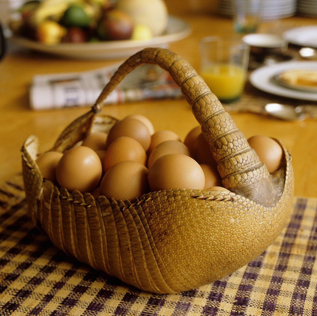 An animal skin basket of eggs on a checked cloth