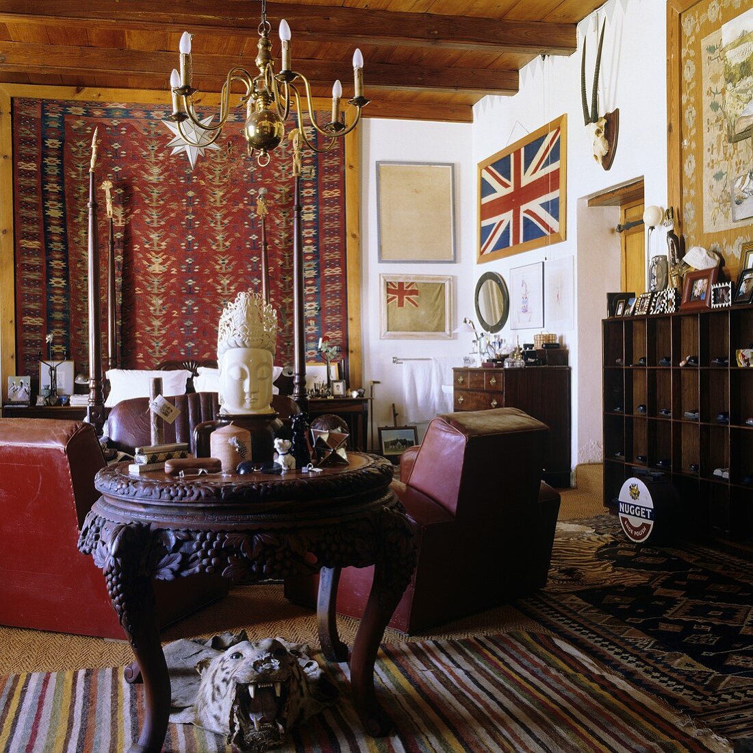 A living room in a South African country house with a dark antique table and a chandelier hanging from the wooden ceiling