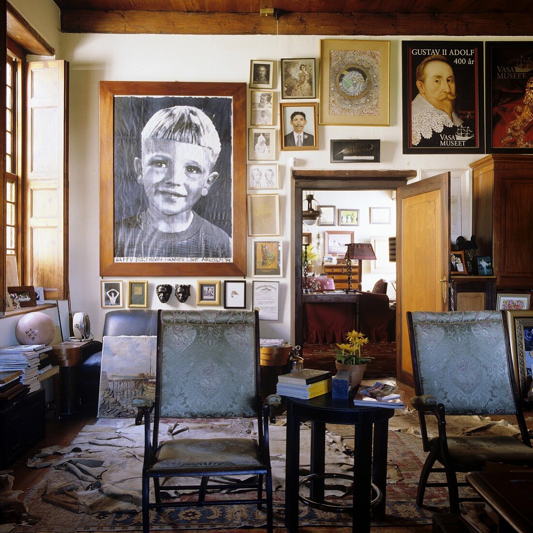 Familienportraits an Wohnzimmerwand und antike Stühle im südafrikanischen Landhaus