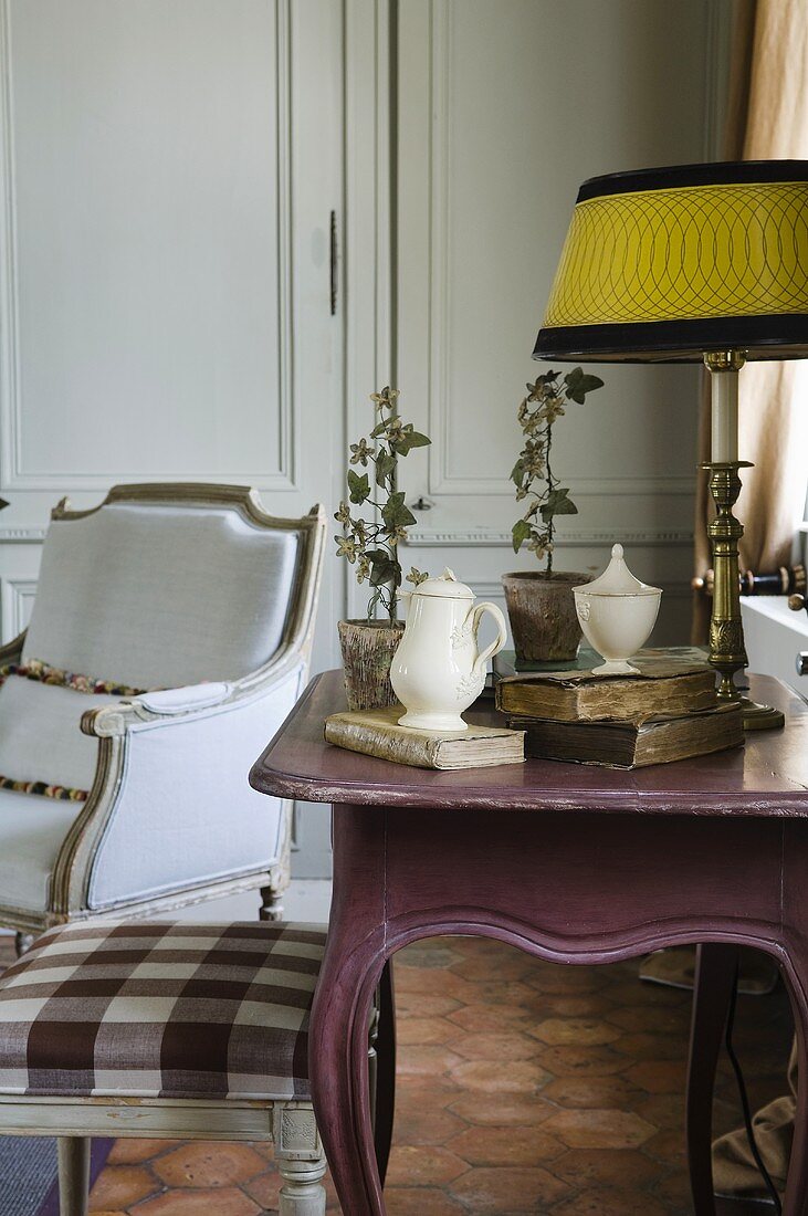 An old fashioned, Rococo-style wall table an armchair and a stool