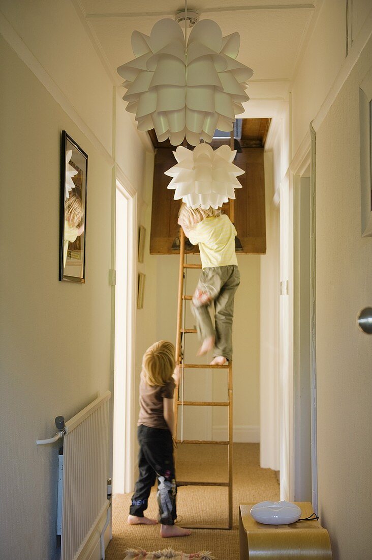 Designer lamps in a hallway and children climbing a ladder
