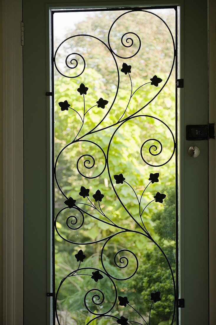 A terrace door with floral metalwork and view into a garden