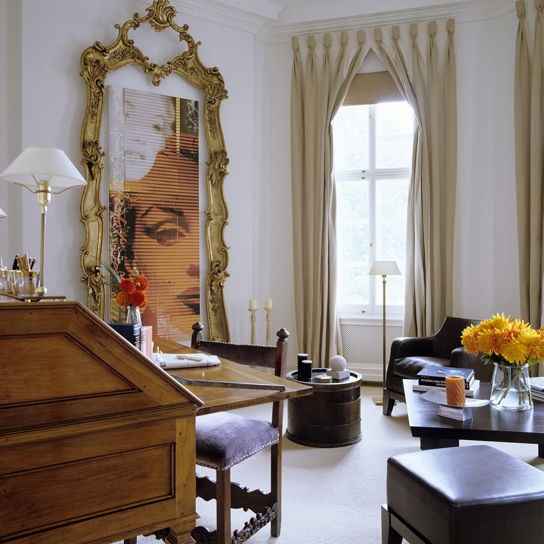 A living room with a gold floor-to-ceiling picture frame and elegant floor-length curtains