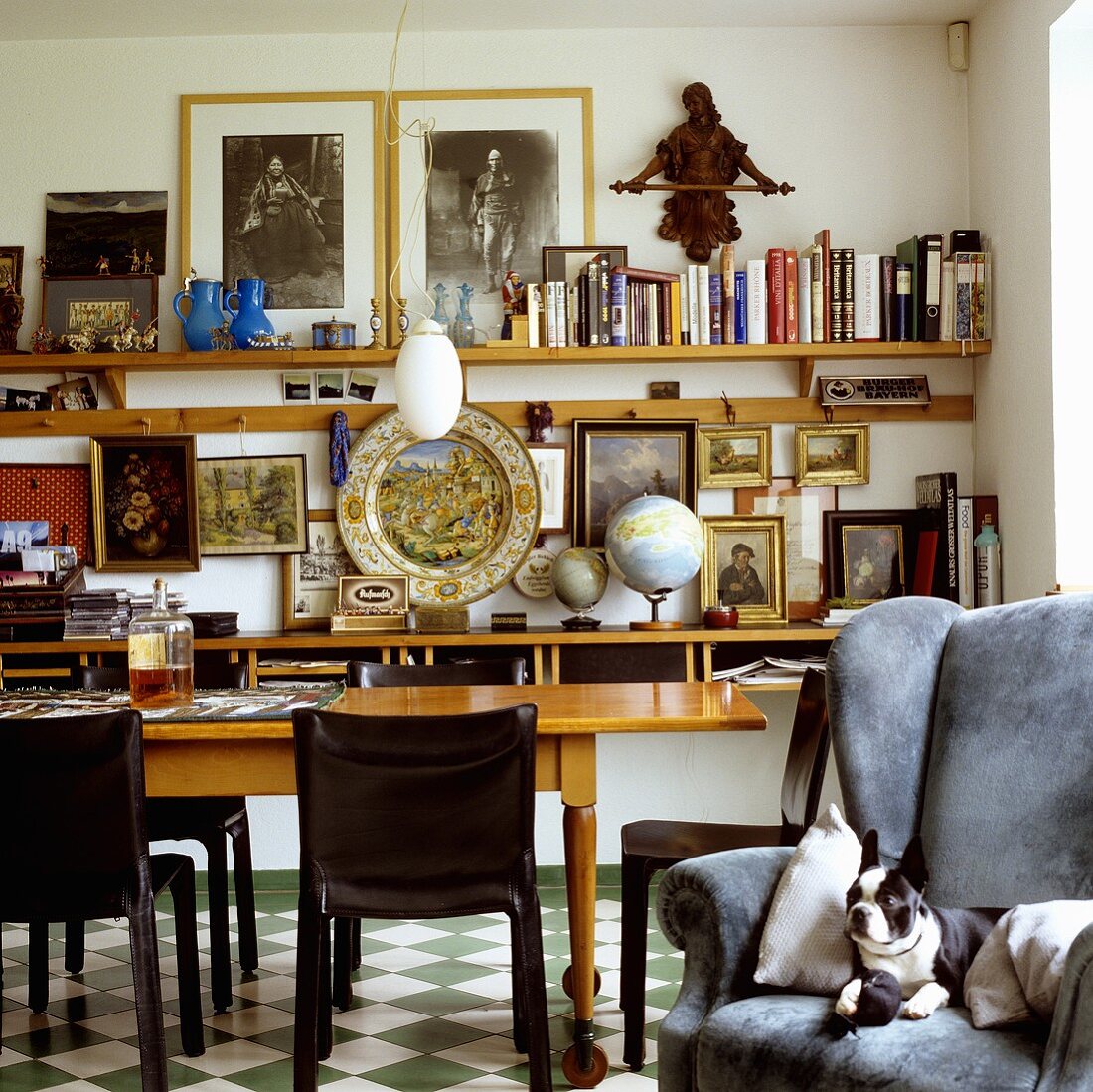A dog lying in an armchair and a dining table in a living room in front of a wall shelf