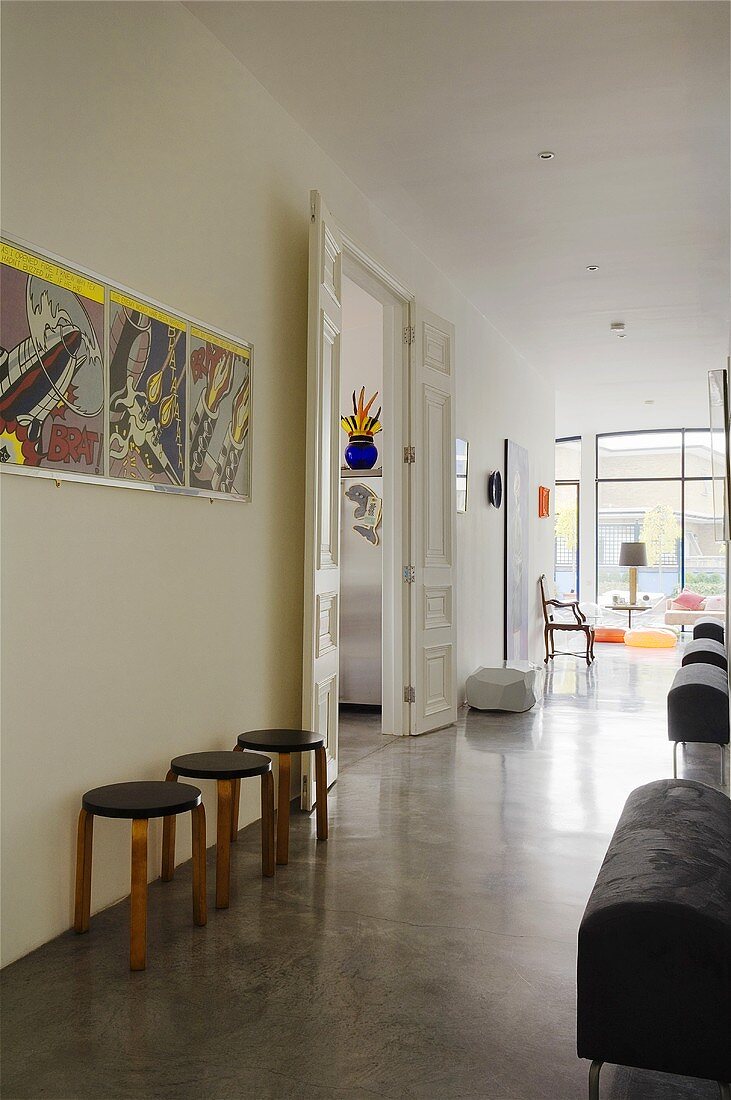 A spacious hallway with a polished screed floor and rows of various seats