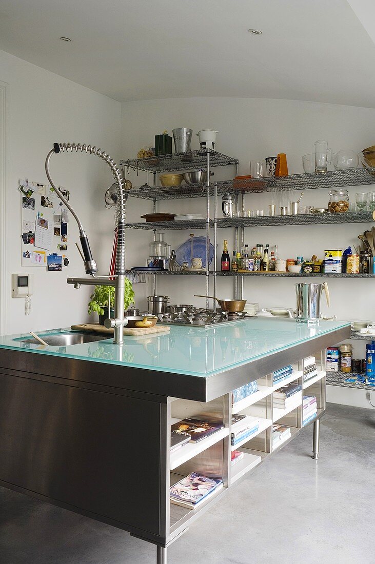 Coole Materialien - Glasplatte auf ausladendem Küchenblock mit Regaleinbau in Edelstahl und moderner Armatur