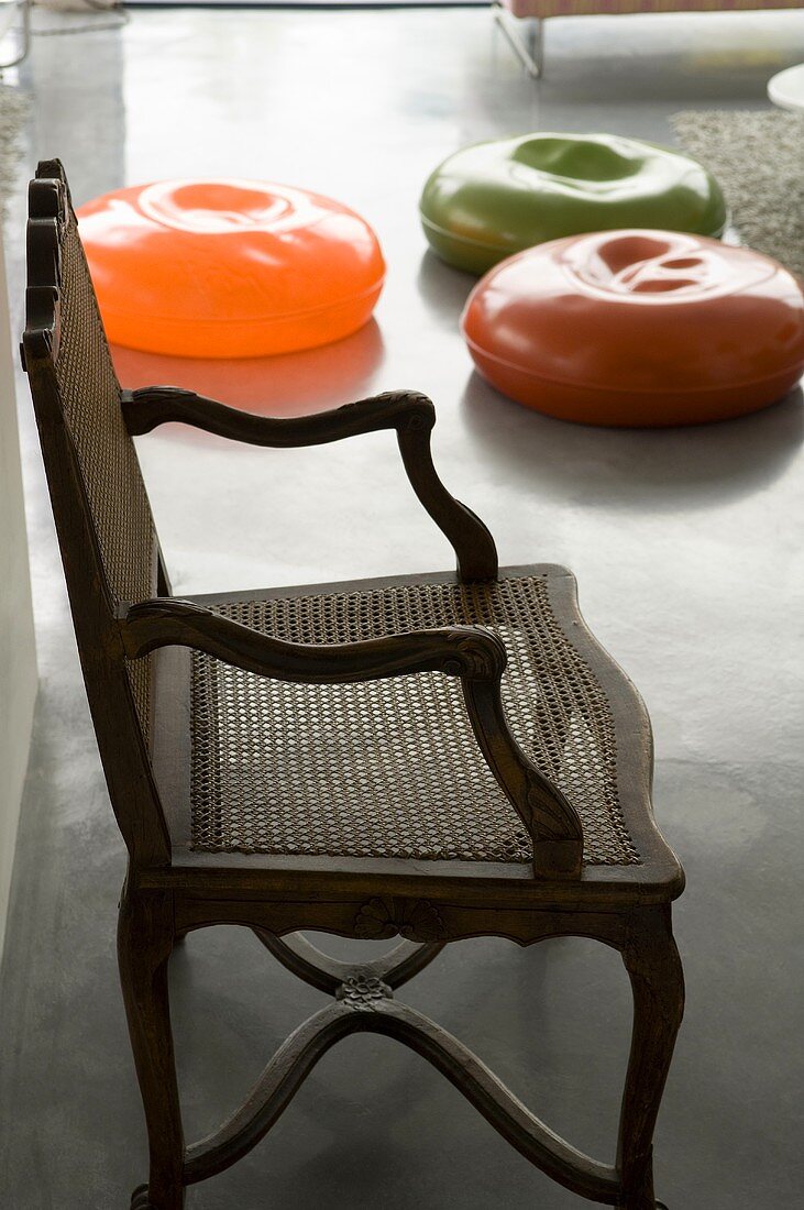 An antique chair and colourful rubber cushions on a concrete floor