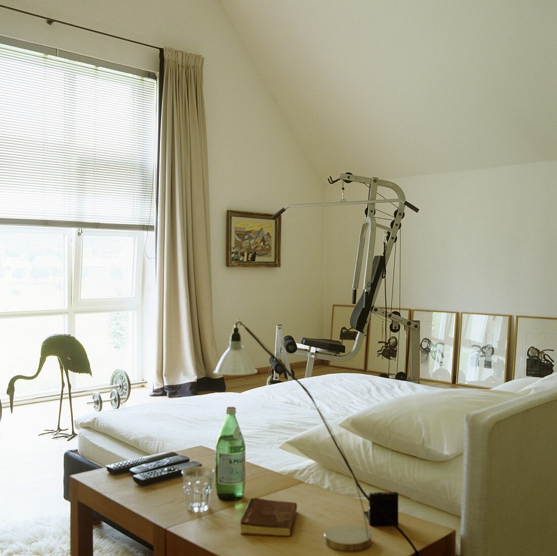 A fitness machine in a simple bedroom with a slopping roof