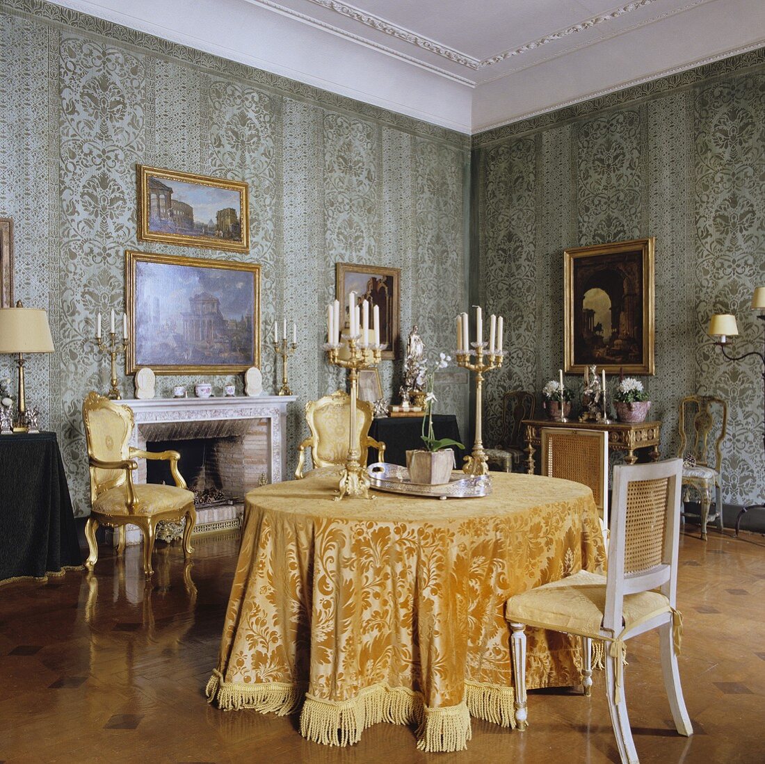 A dining room in a palazzo with antique candlesticks on the table and Rococo-style chairs