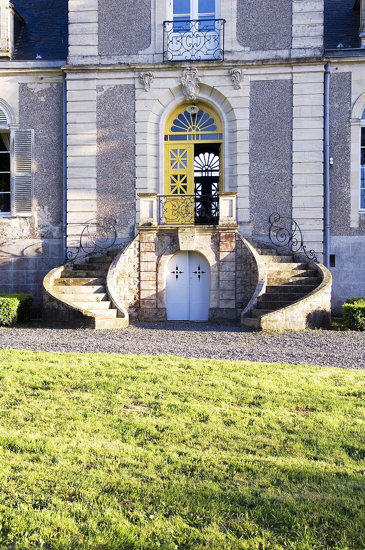 Blick über Rasen auf Landhaus mit geschwungenem Treppenaufgang zum Hauseingang