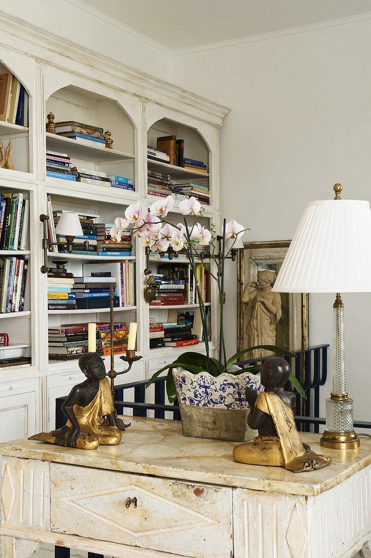 Wooden figurines and an antique table lamp on a side table with a marble top