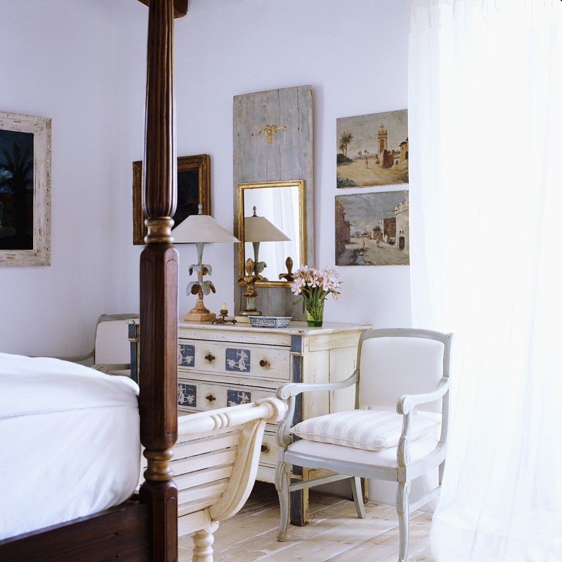 A bedroom with antique, white-painted country house-style furniture