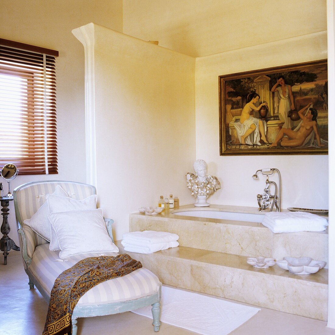 A bathroom with a chaise longue in front of a marble bathtub with steps