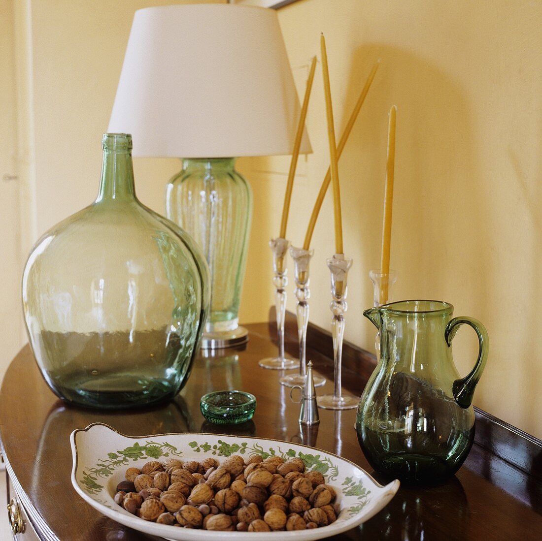 A bowl of nuts and a carafe on a shelf