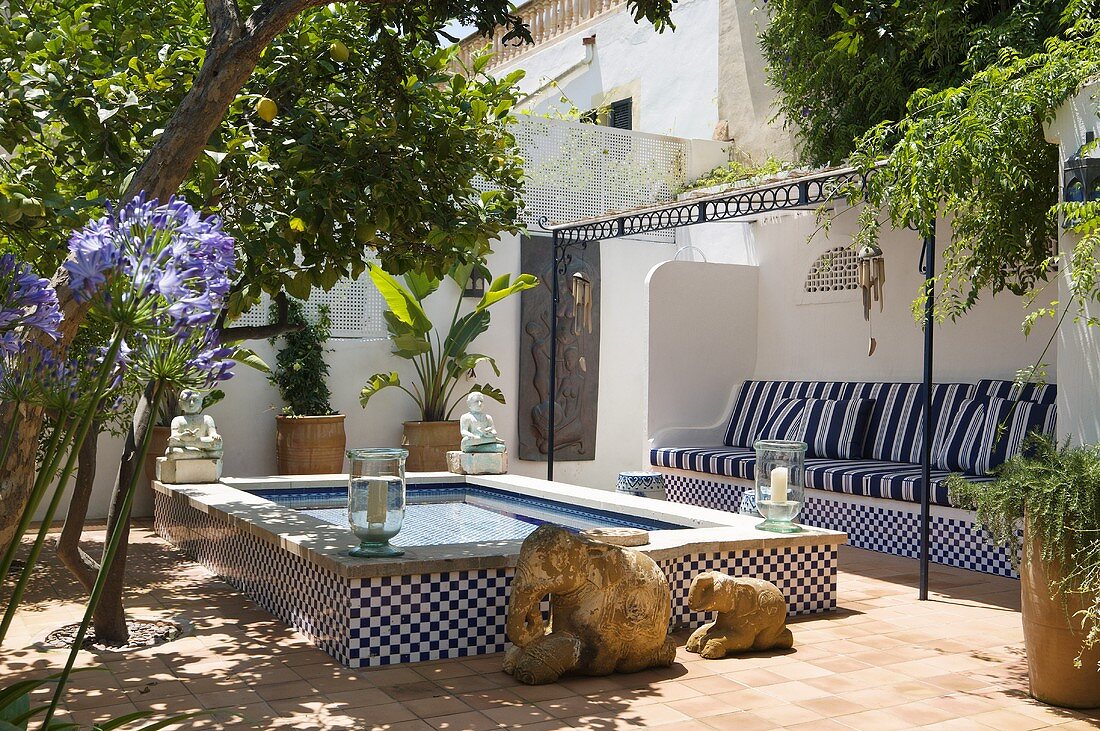 A tiled water fountain in a Mediterranean courtyard with potted plants