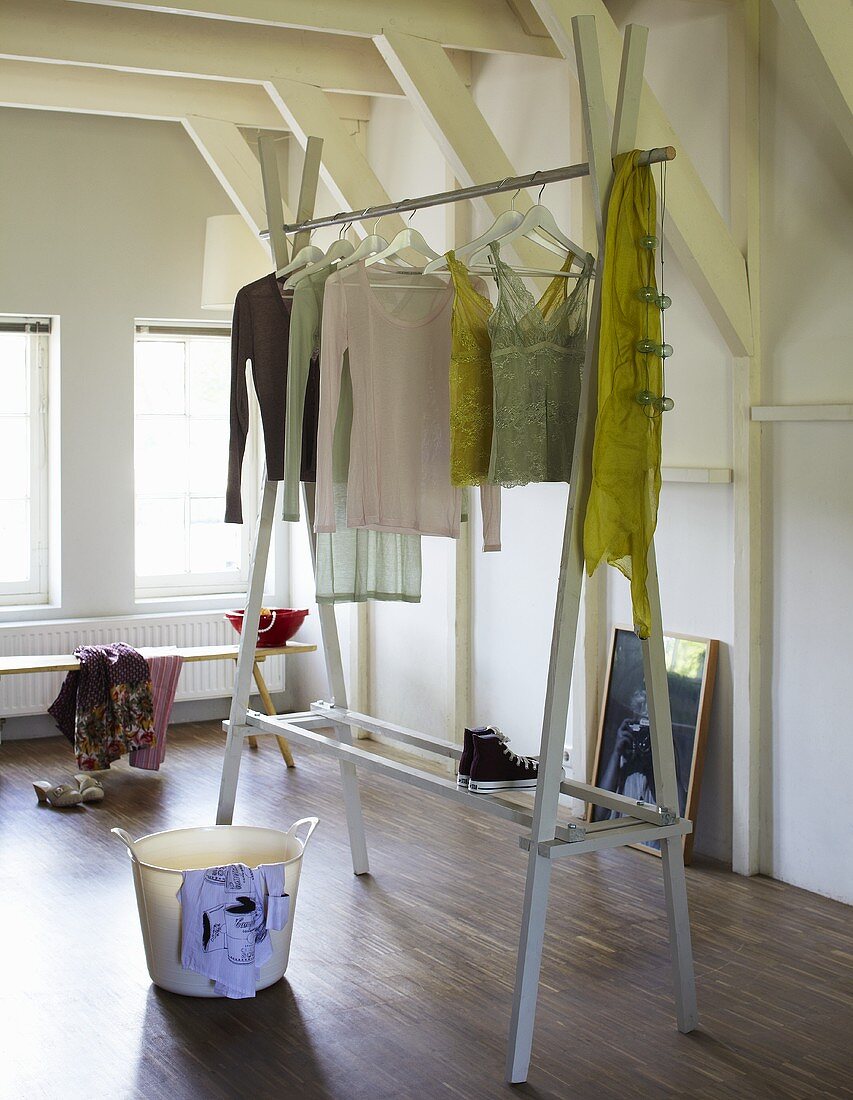 Clothes hanging on a homemade clothes rack in a white-painted attic room