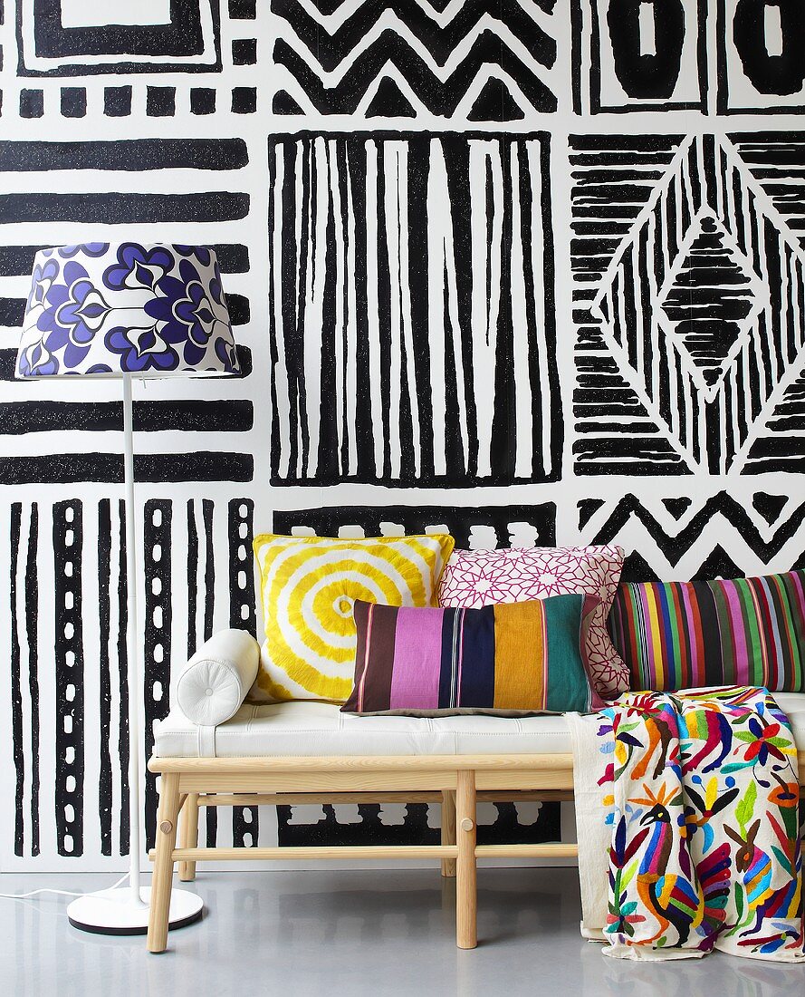 Colours contrasting with black and white - cushions on an upholstered bench in from of a painted wall
