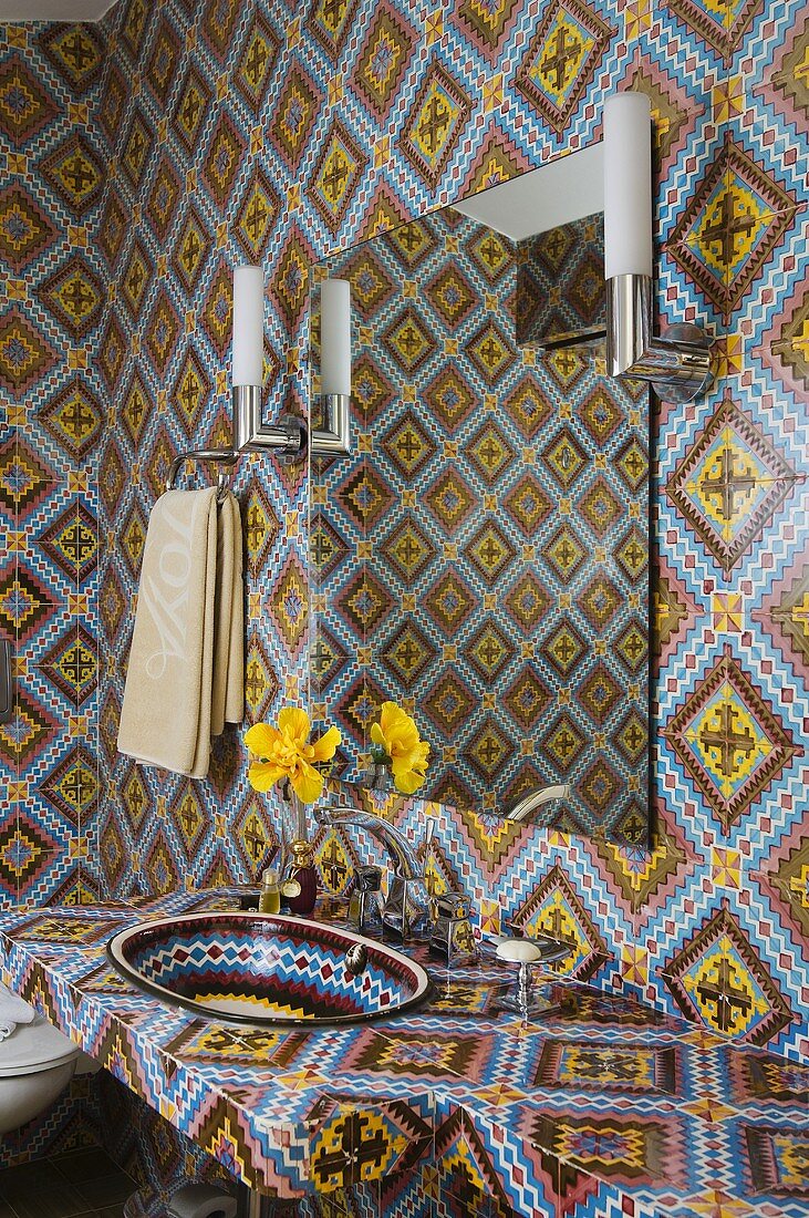 Mediterranean tiled pattern on a washstand and a wall with a mirror and wall lamps