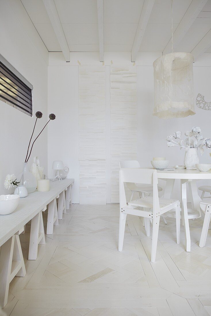 An artistic room design - white containers on a trestle table and a white dining area