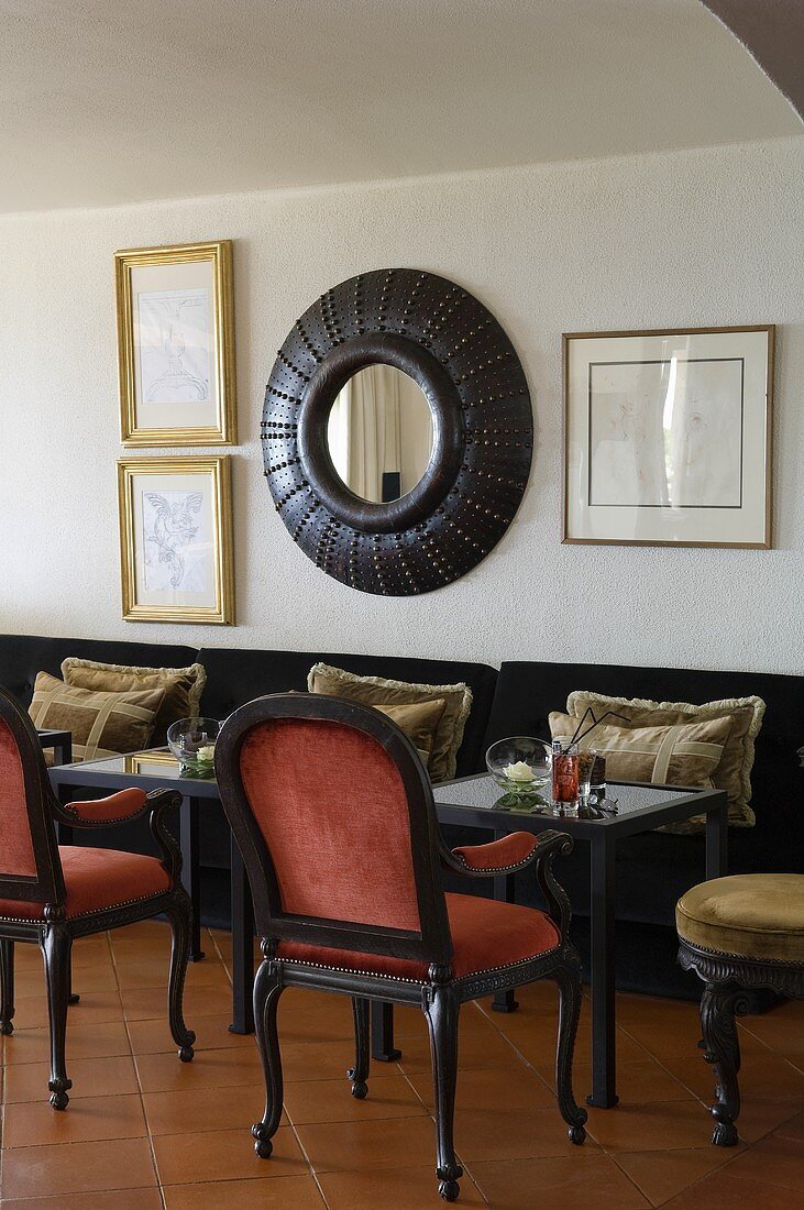 Antique chairs with bistro tables in a hotel bar and a framed mirror on the wall
