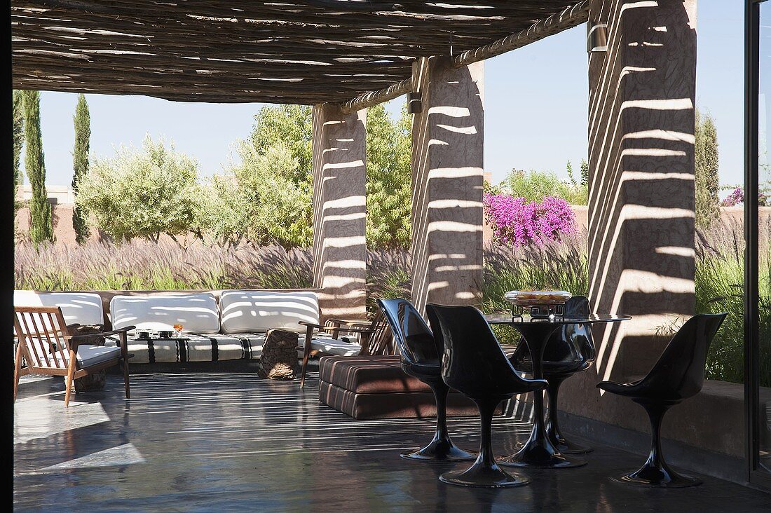A Mediterranean garden - a covered terrace with black plastic chairs on a polished concrete floor