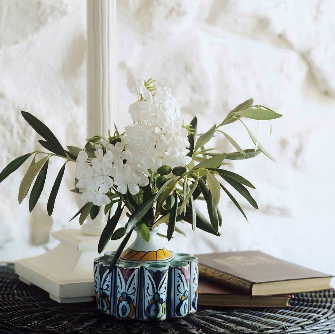 weiße Blumen und Olivenzweige in einer Vase