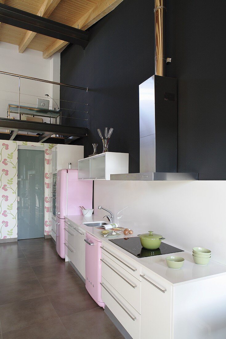 An open-plan kitchen - a kitchen counter in front of a black wall and view of a gallery
