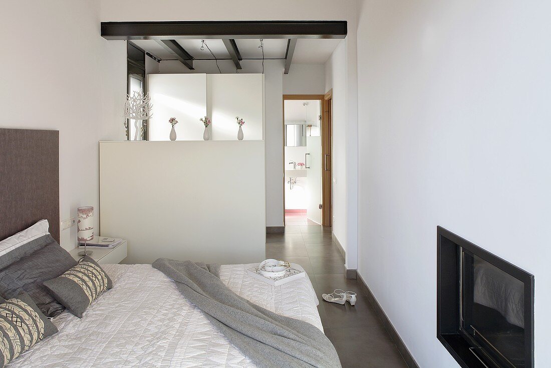 A bedroom with built-in television, a room divider and a view in a bathroom