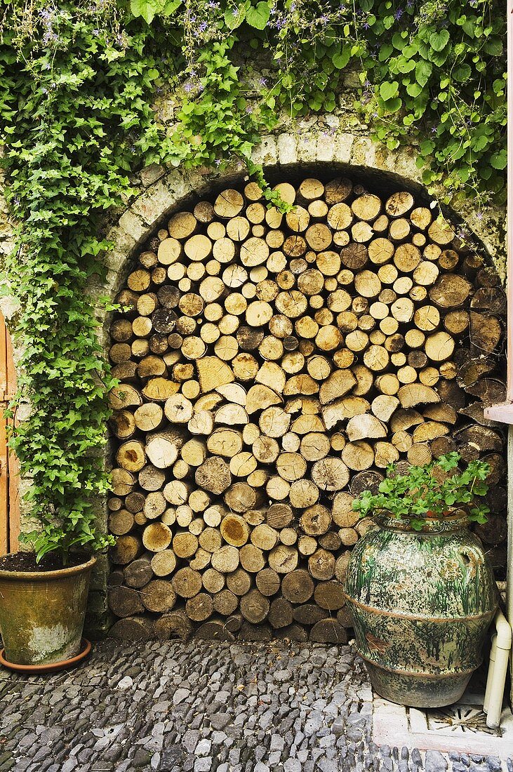 A rounded archway in a courtyard filled with firewood