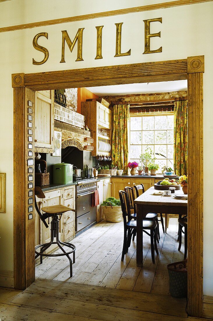 The word 'Smile' written above a doorway with a view into a country house kitchen