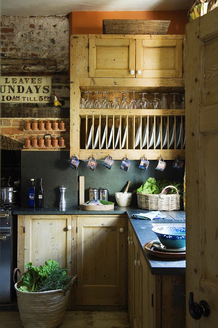 A rustic fitted kitchen with wooden cupboards and a built-in plate rack