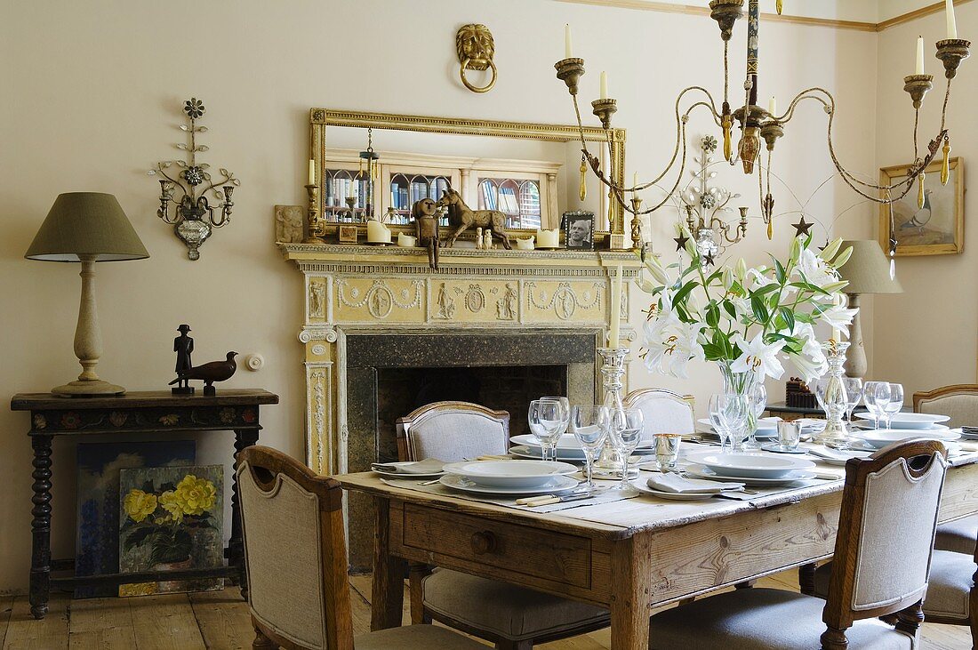 An dinner invitation - a table laid in the fireplace room of a country house with a chandelier hanging from the ceiling