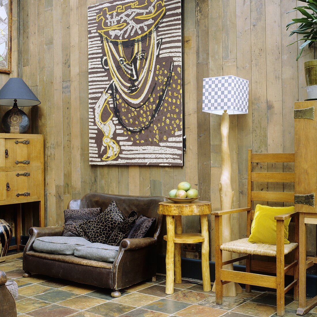 Rustikaler Raum mit Ledersessel und selbstgebauten Möbeln vor Holzwand
