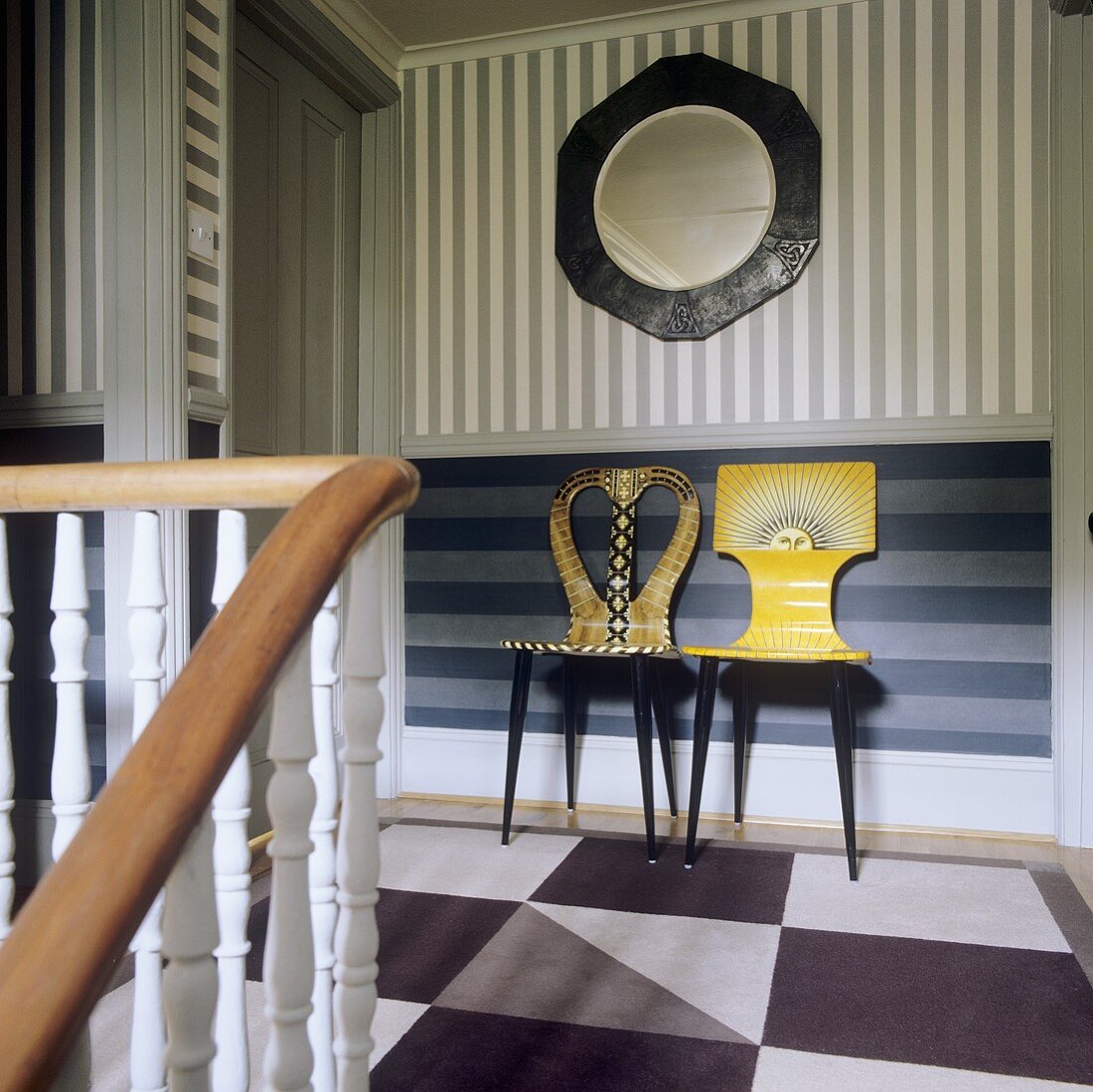 Artistically painted chairs against a striped wall in a stairway