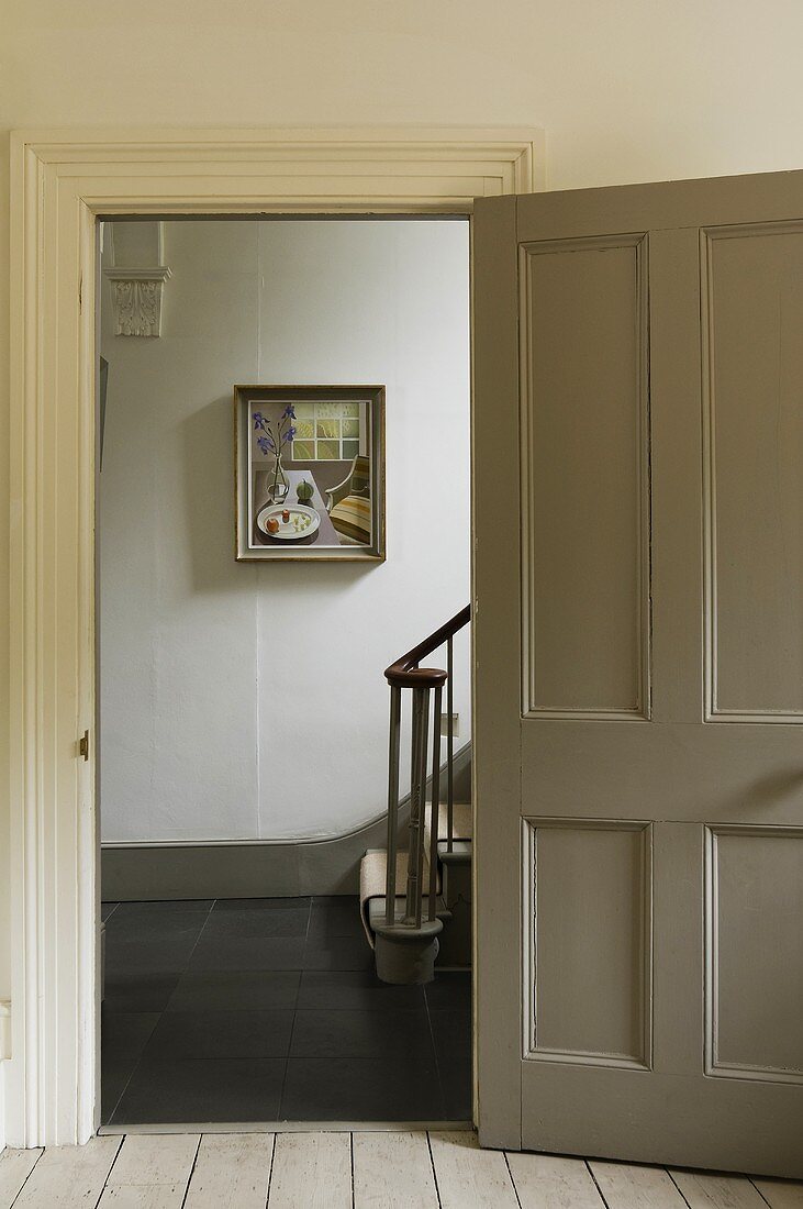 An open door with a view into a stairway with a picture on the wall