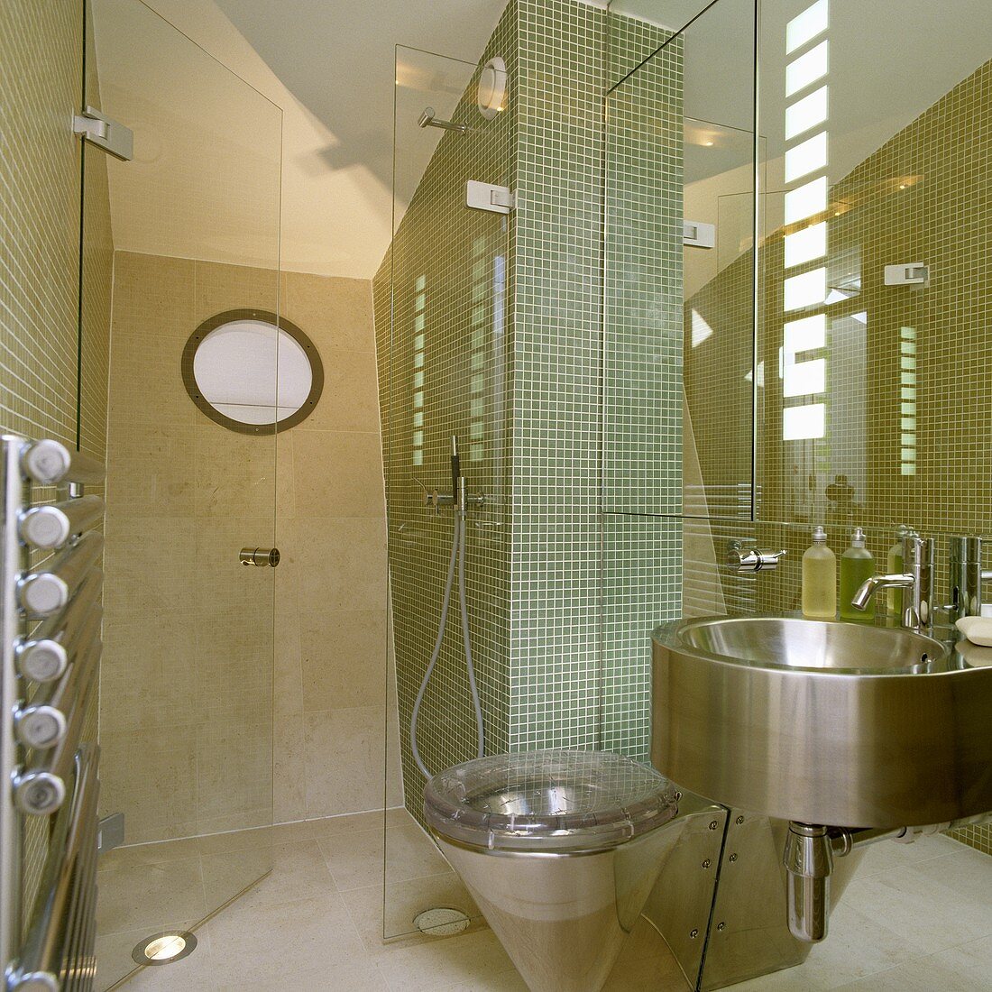 Designtes Bad - Edelstahlbecken und Toilette vor Spiegelfront und Mosaikfliesen im Duschbereich