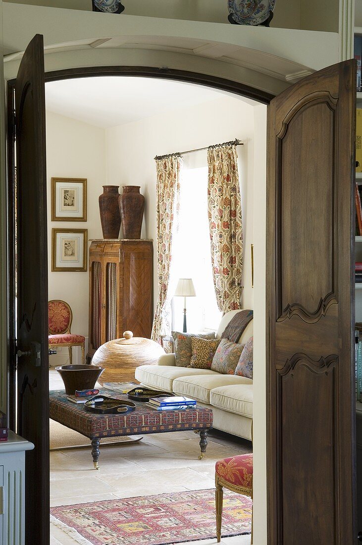 A view through an open wooden double door of a coffee table and an upholstered sofa