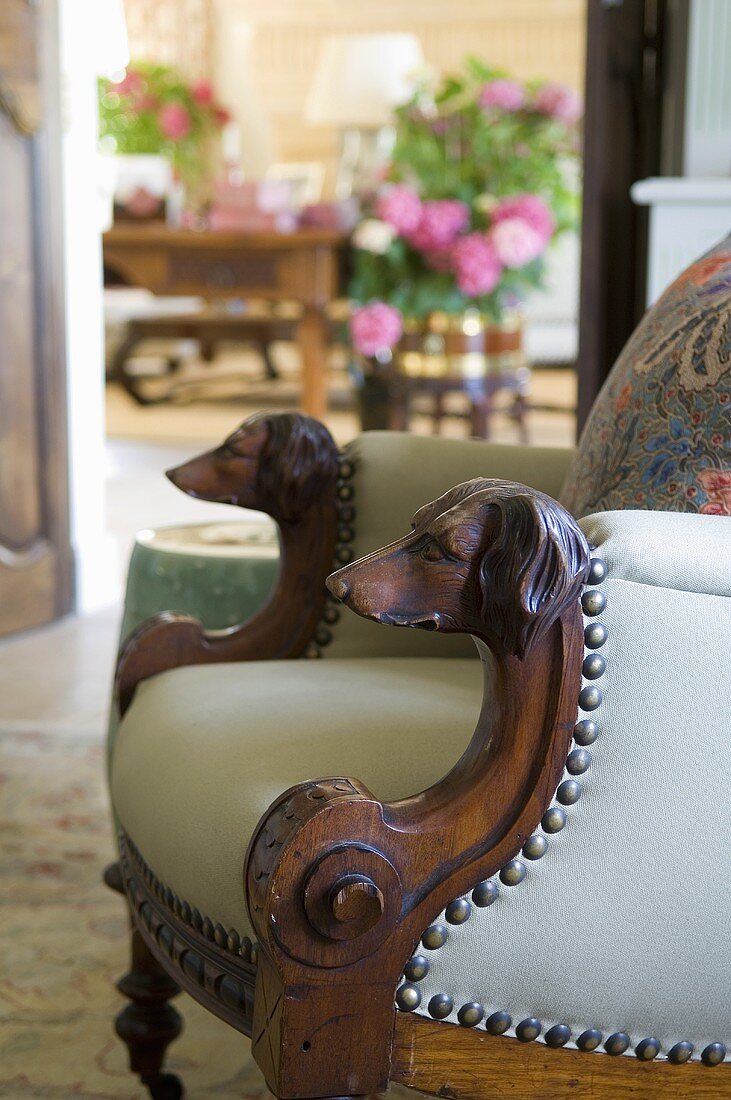 An antique leather chair with wooden arm rests carved with dog heads