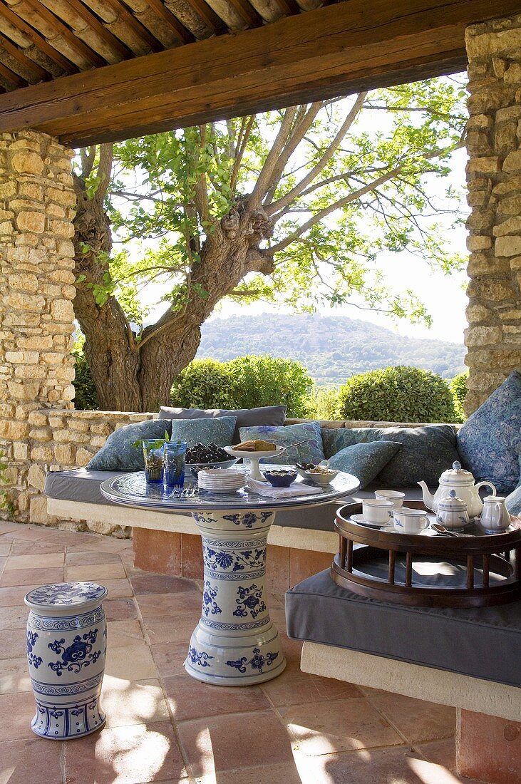 A coffee break on a terrace with an upholstered corner bench and a view of the Mediterranean landscape