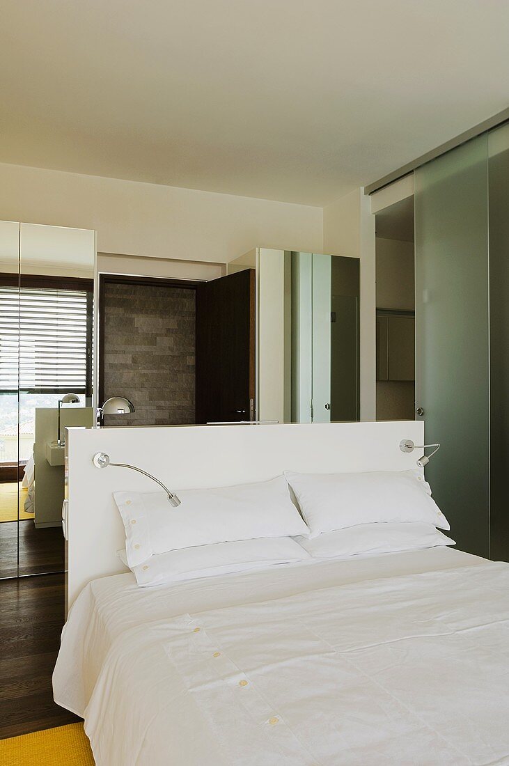 Doppelbett mit weisser Bettwäsche und Spiegelschränke im Schlafraum