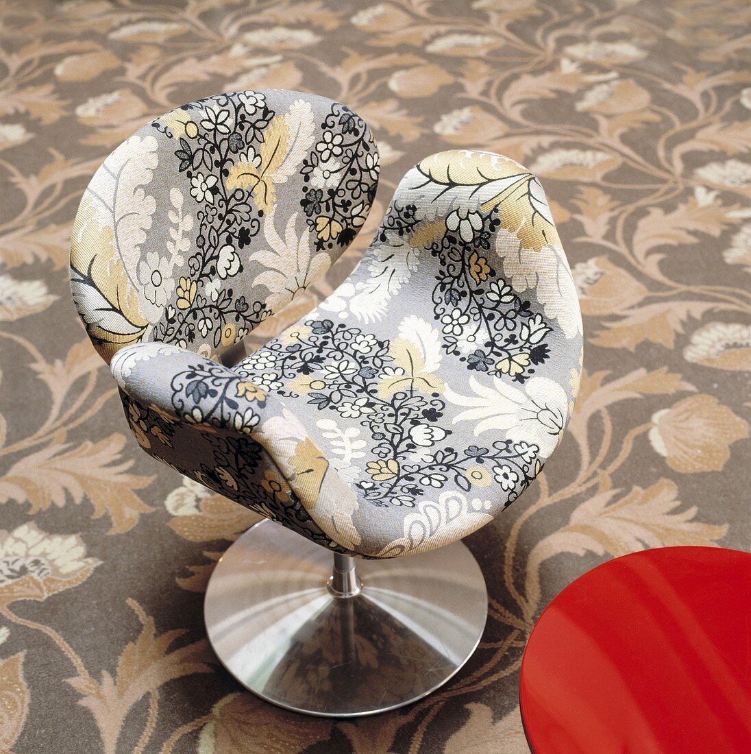 Blumenmuster auf gepolstertem Designerstuhl mit Metallfuss und floraler Teppich