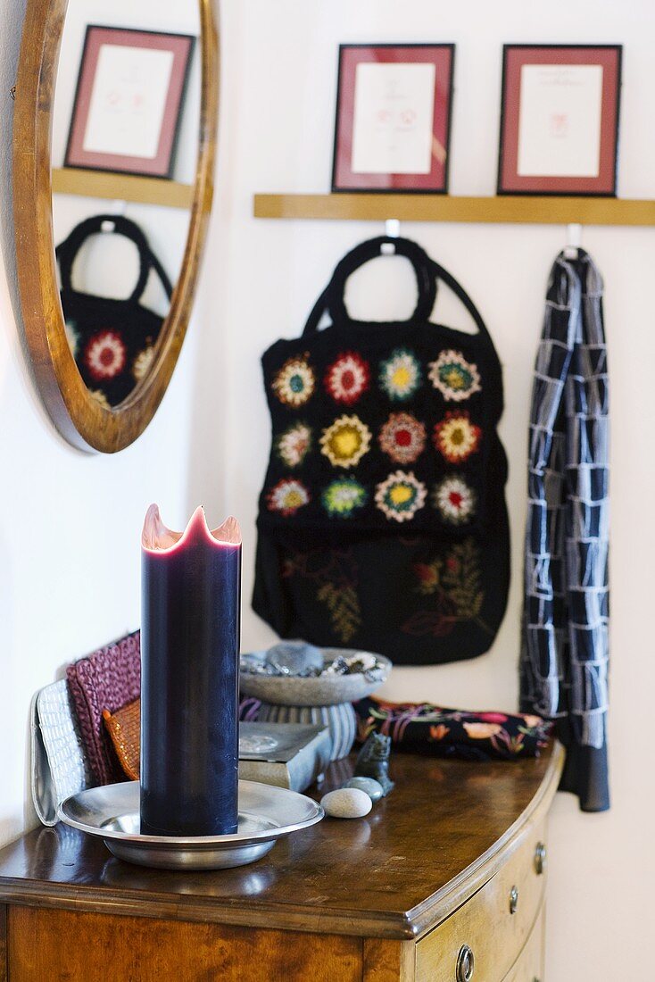 Candles on a chest of drawers and bags hanging on hooks