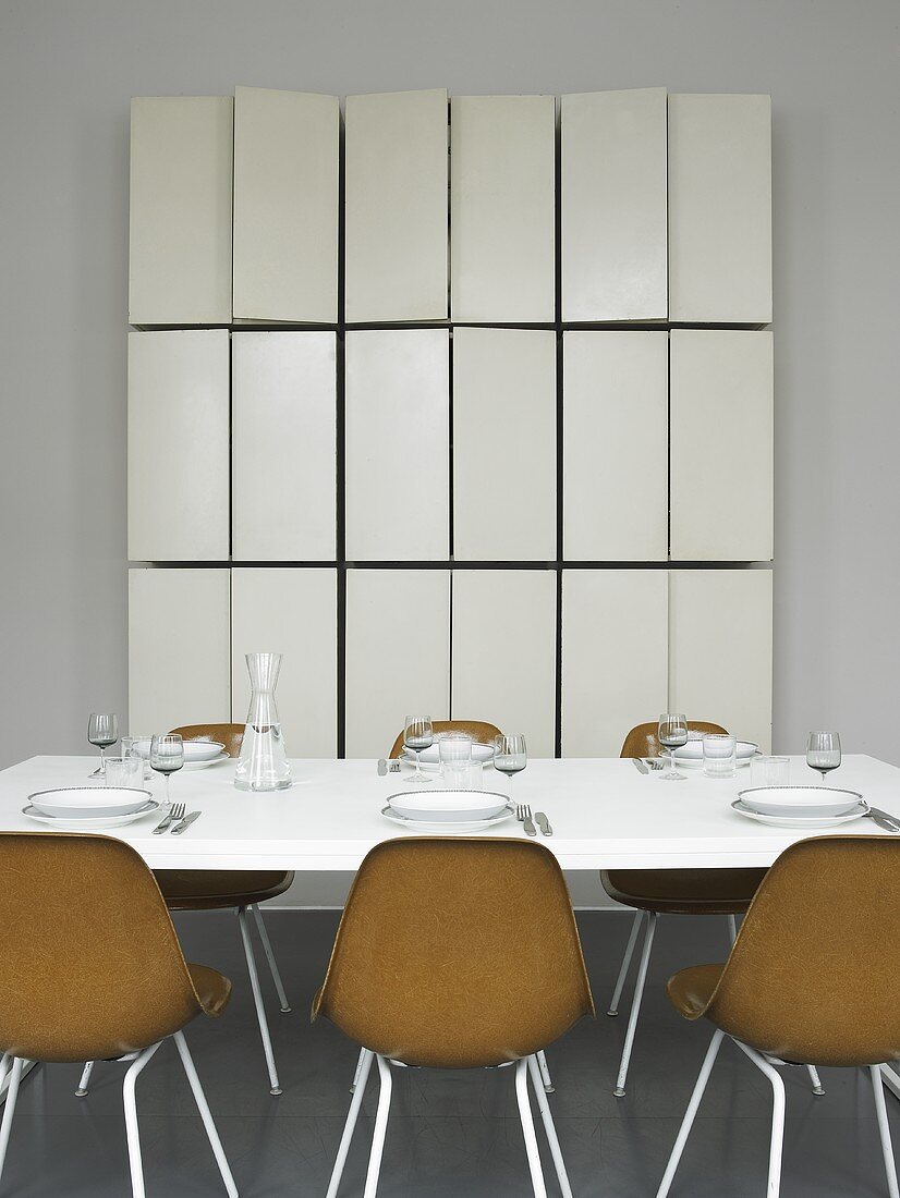 Gedeckter Tisch mit braunen Schalenstühlen und massgefertigtem Wandschrank mit offenen Türen