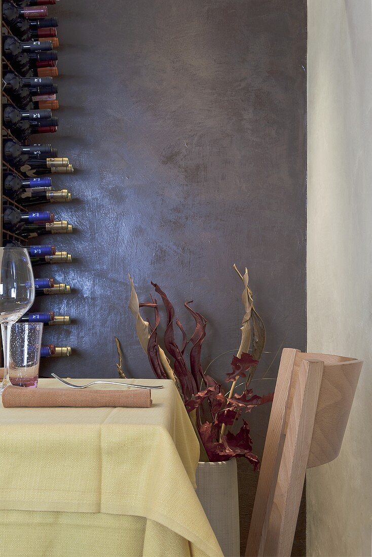 Zimmerecke im Designer Restaurant - Tisch mit Stuhl und Weinregal vor dunkler glänzender Wand