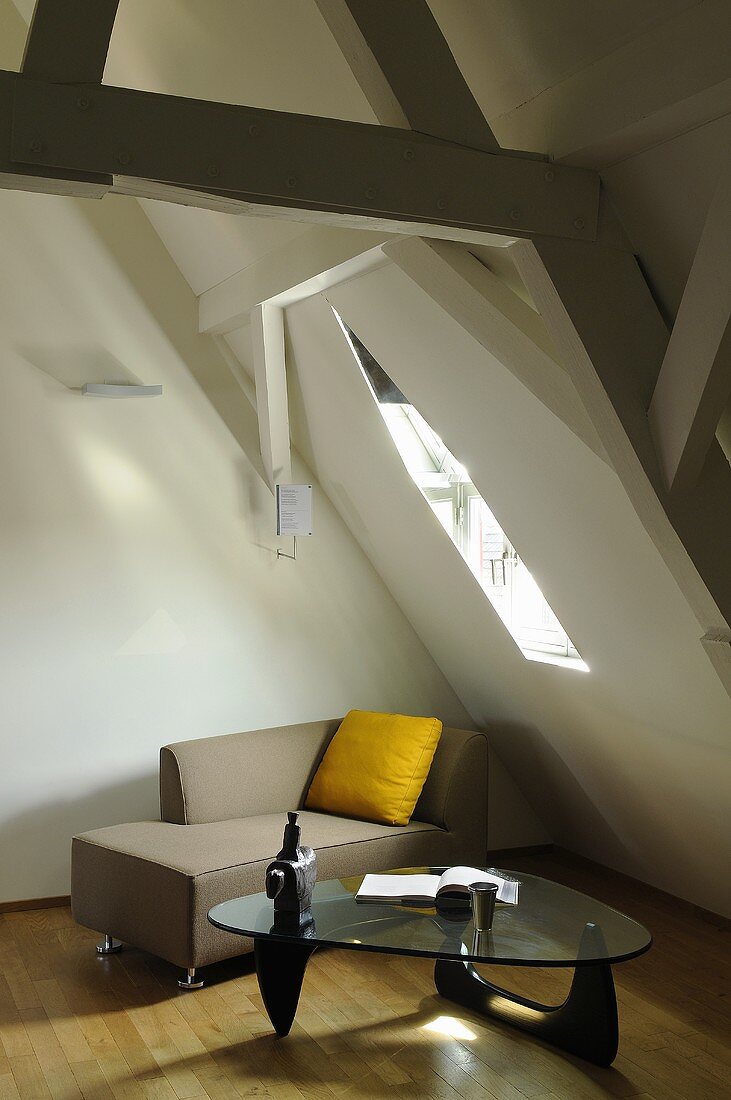 A renovated attic with a modern chaise longue under the skylight