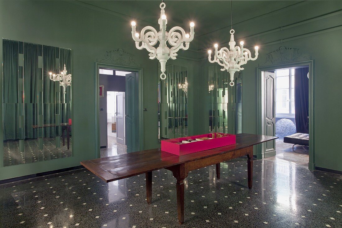 Luxuriöser Vorraum mit grauer Wand und antiker Holztisch unter weissen Kerzenleuchtern