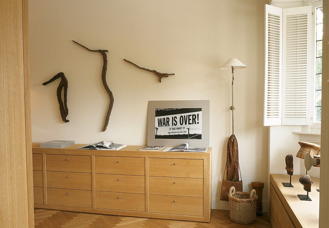 A light wood sideboard with drawers and a decorated wall