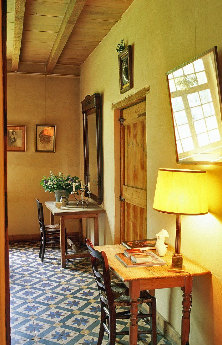 A chair and a wall table in the hallway of a country house with a tiled floor