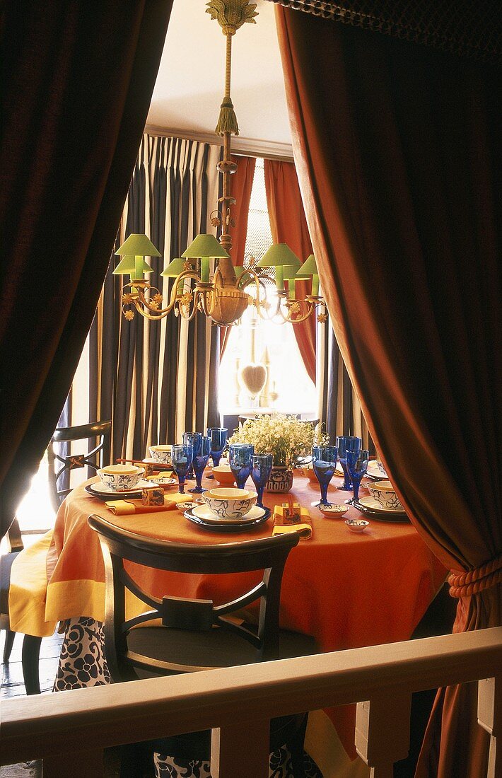 Blick durch Vorhang - Kronleuchter mit grünen Schirmen und gedeckter Tisch